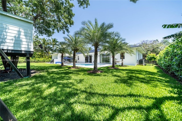 view of yard featuring an outdoor pool and central AC