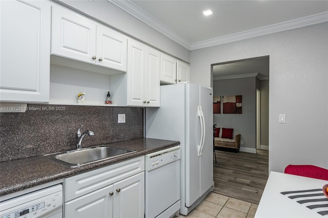 kitchen featuring a sink, white dishwasher, washer / dryer, crown molding, and white cabinets