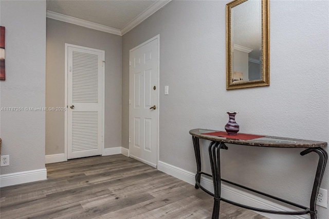 foyer featuring baseboards, ornamental molding, and wood finished floors
