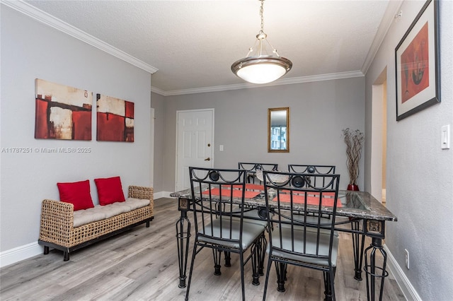dining space with crown molding, a textured ceiling, wood finished floors, and baseboards