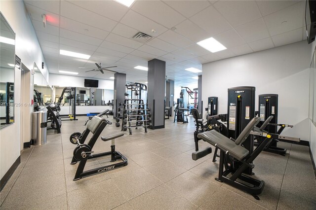 workout area with a paneled ceiling, ceiling fan, baseboards, and visible vents