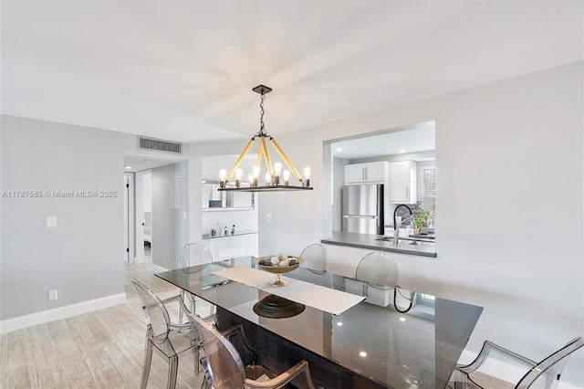 dining room featuring light wood-style floors, visible vents, baseboards, and an inviting chandelier