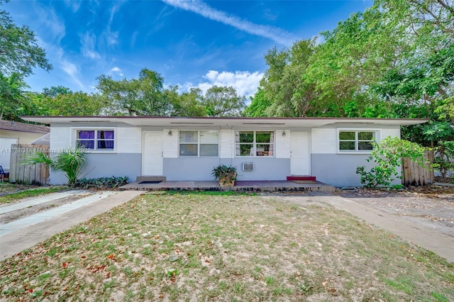 ranch-style home with stucco siding, a front lawn, covered porch, and fence