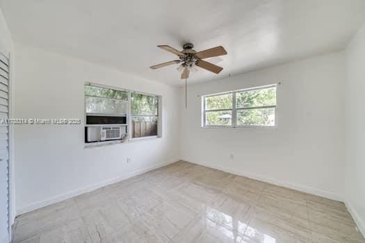 spare room featuring baseboards, a ceiling fan, and cooling unit