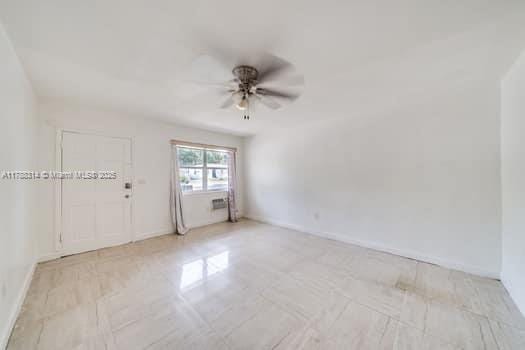empty room with ceiling fan and baseboards