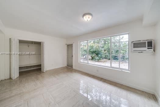 unfurnished bedroom featuring baseboards, a closet, and a wall unit AC