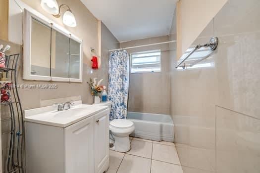 bathroom with tile patterned flooring, toilet, vanity, and shower / bathtub combination with curtain