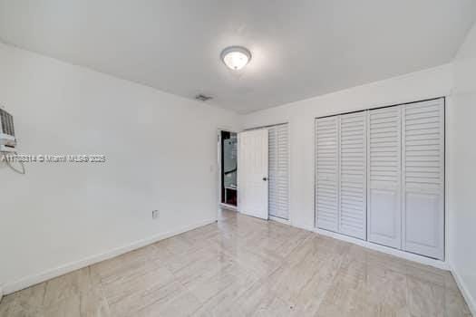 unfurnished bedroom featuring multiple closets and baseboards
