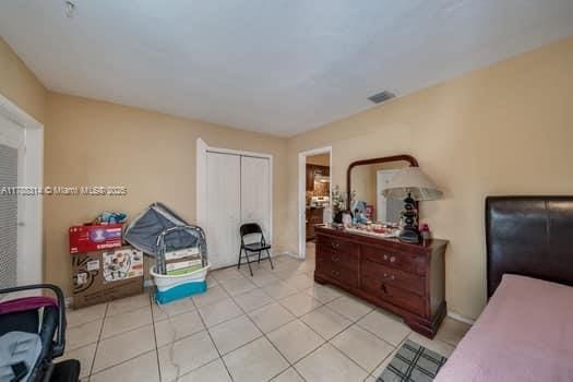 bedroom with a closet, visible vents, and light tile patterned floors