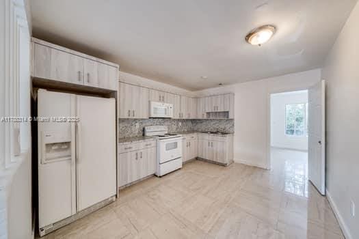 kitchen with decorative backsplash, baseboards, white appliances, and white cabinets