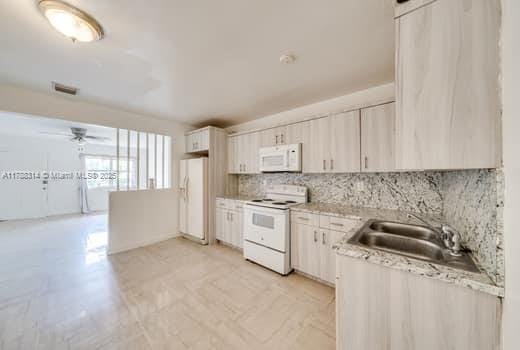 kitchen featuring light countertops, visible vents, a ceiling fan, white appliances, and decorative backsplash