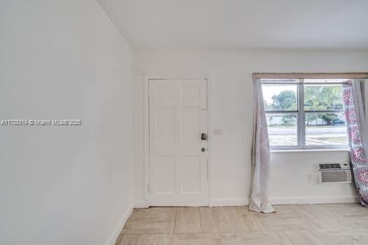 foyer entrance with baseboards and a wall mounted AC