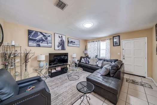 living area featuring baseboards, visible vents, and light tile patterned floors