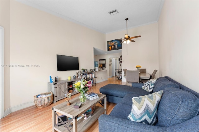 living room with ceiling fan, light wood-type flooring, crown molding, and baseboards