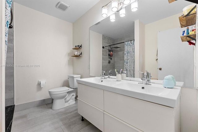 full bath featuring toilet, a tile shower, baseboards, and double vanity