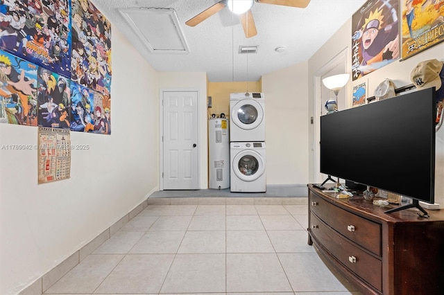 washroom featuring stacked washing machine and dryer, water heater, a textured ceiling, a ceiling fan, and baseboards