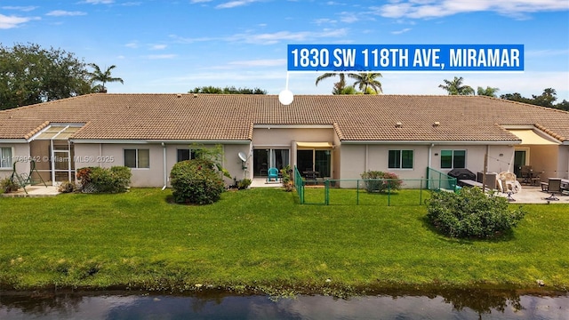 back of property featuring a patio area, a tile roof, and a water view