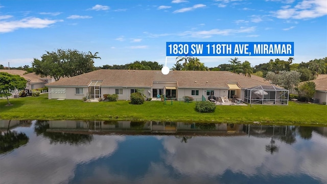 rear view of house with a water view, a yard, and a lanai