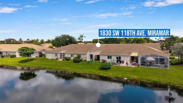 rear view of property with a water view, a yard, and a patio area
