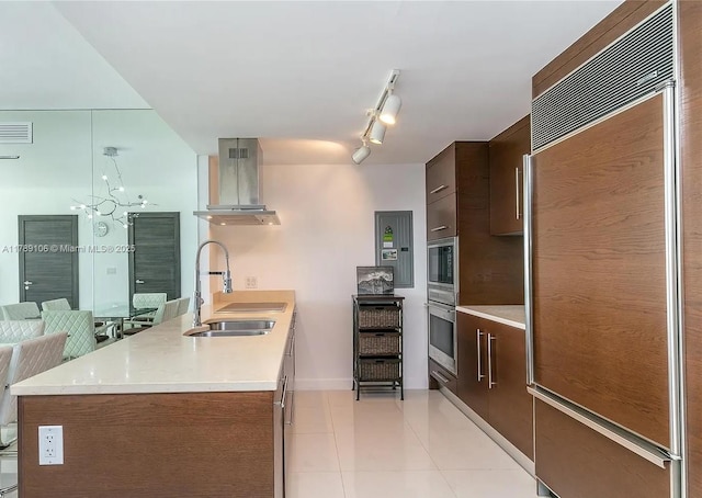 kitchen with exhaust hood, a sink, modern cabinets, built in appliances, and light countertops