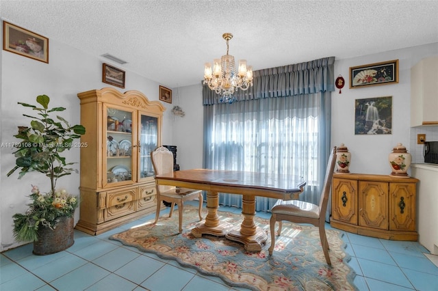 dining room featuring a textured ceiling, tile patterned flooring, a notable chandelier, and visible vents