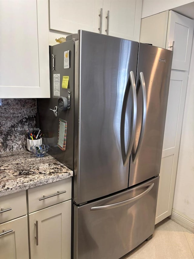 500 Three Islands Blvd Unit 313, Hallandale Beach, FL 33009 - kitchen featuring freestanding refrigerator, light stone countertops, baseboards, white cabinetry, and light tile patterned floors