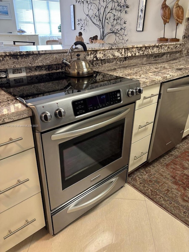 500 Three Islands Blvd Unit 313, Hallandale Beach, FL 33009 - kitchen with stainless steel appliances, light tile patterned floors, and stone counters