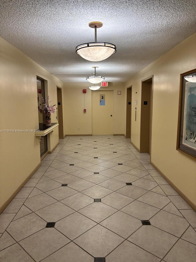 500 Three Islands Blvd Unit 313, Hallandale Beach, FL 33009 - corridor with elevator, a textured ceiling, light tile patterned floors, and baseboards