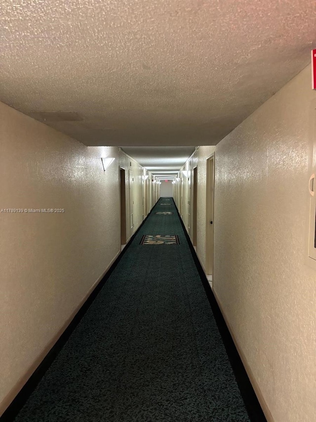 500 Three Islands Blvd Unit 313, Hallandale Beach, FL 33009 - corridor with a textured wall, a textured ceiling, and dark carpet