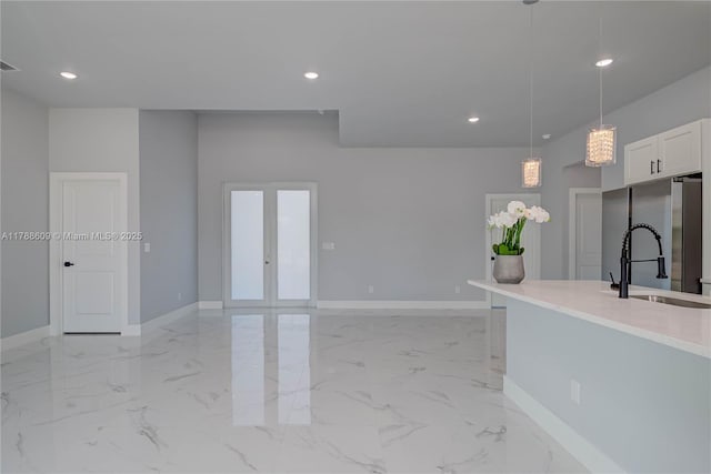 kitchen featuring freestanding refrigerator, hanging light fixtures, baseboards, and a sink