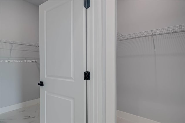 walk in closet with marble finish floor