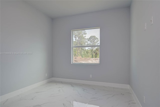 unfurnished room with marble finish floor and baseboards