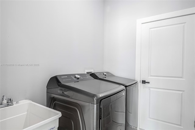 clothes washing area with a sink, independent washer and dryer, and laundry area