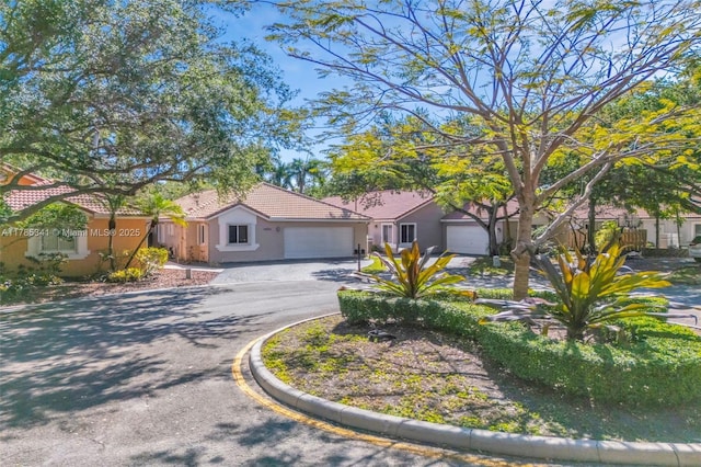 view of front of home with stucco siding, a tile roof, a garage, and aphalt driveway