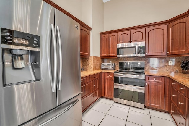 kitchen featuring light stone countertops, appliances with stainless steel finishes, decorative backsplash, and light tile patterned floors