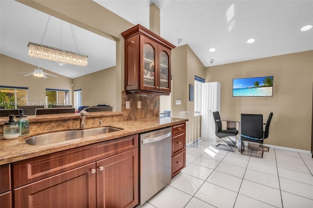 kitchen with lofted ceiling, backsplash, stainless steel dishwasher, a sink, and light stone countertops