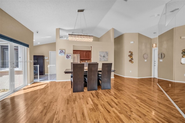 dining room with vaulted ceiling, light wood-style flooring, and baseboards