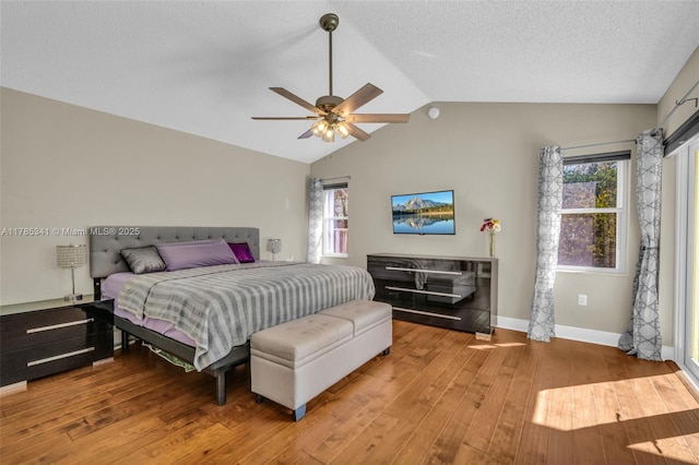 bedroom with lofted ceiling, wood finished floors, a ceiling fan, baseboards, and a textured ceiling