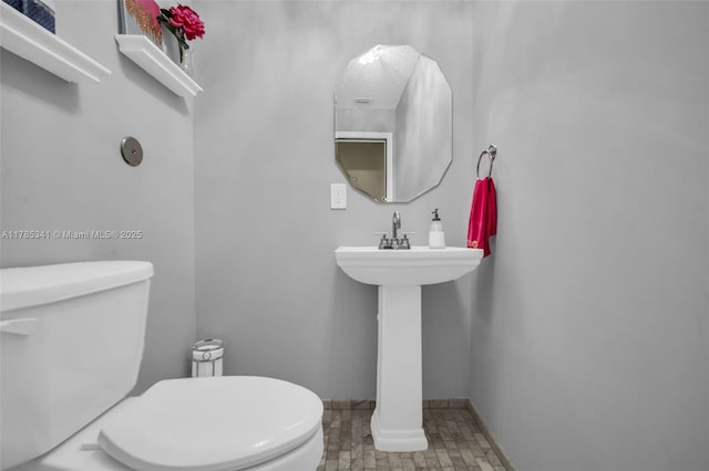 half bathroom featuring toilet and baseboards