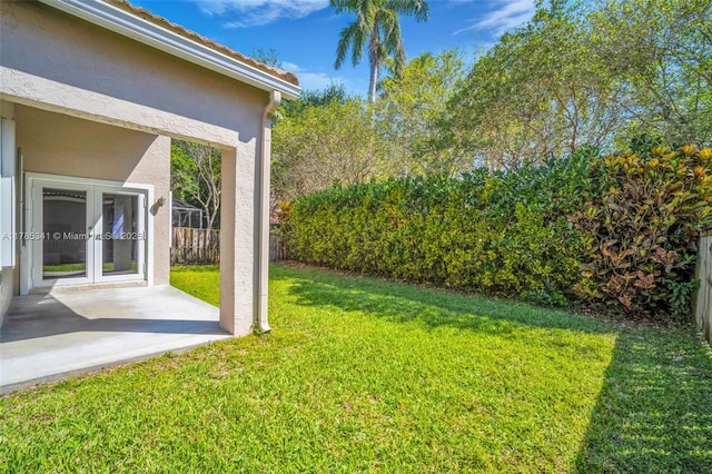 view of yard with fence, a patio area, and french doors