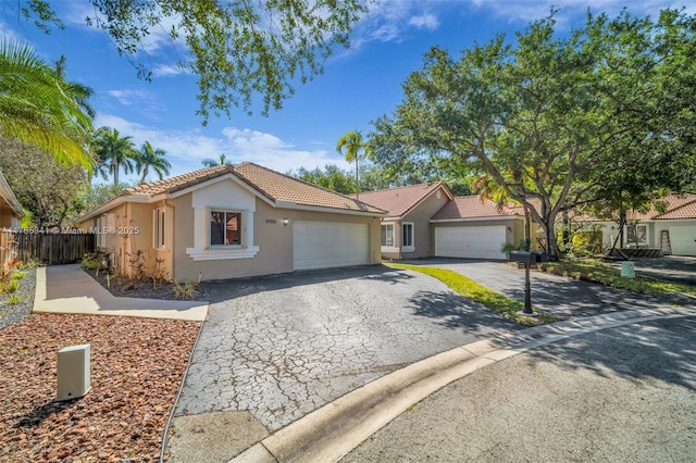 ranch-style house featuring aphalt driveway, fence, a tiled roof, stucco siding, and a garage