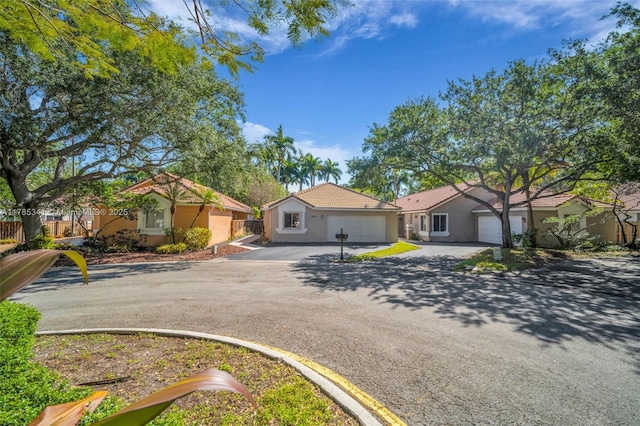 view of front facade featuring a garage, driveway, stucco siding, and fence