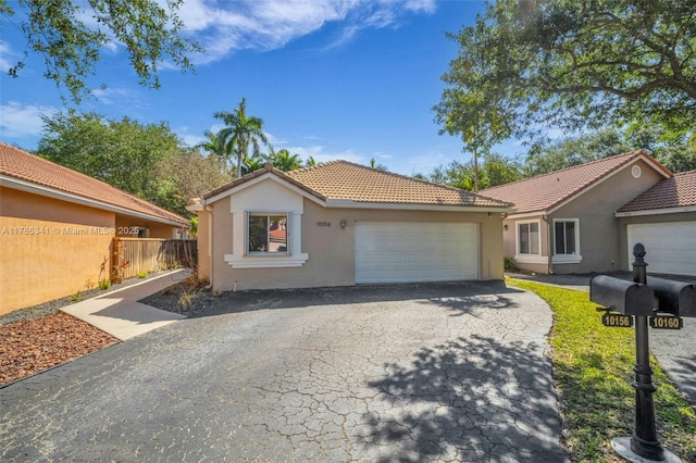 single story home featuring a tiled roof, aphalt driveway, fence, a garage, and stucco siding