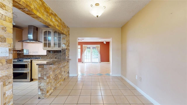 6051 SW 110th Ave, Miami, FL 33173 - kitchen with glass insert cabinets, wall chimney exhaust hood, tasteful backsplash, range with two ovens, and light tile patterned floors