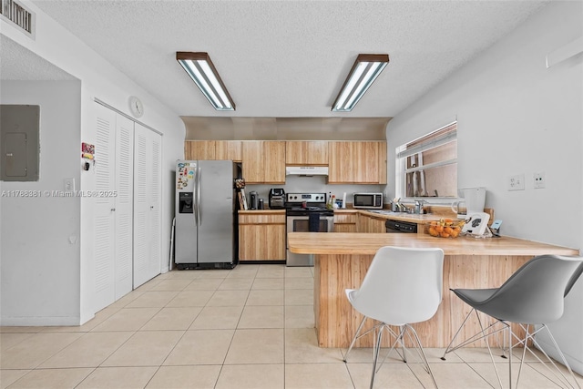 1341 NW 123rd Ter Unit 1341, Pembroke Pines, FL 33026 - kitchen with a peninsula, visible vents, a kitchen bar, under cabinet range hood, and appliances with stainless steel finishes