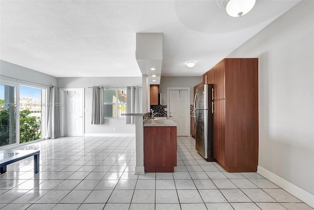2200 S Ocean Dr Unit N116, Hollywood, FL 33019 - kitchen featuring brown cabinetry, freestanding refrigerator, a peninsula, baseboards, and light tile patterned floors