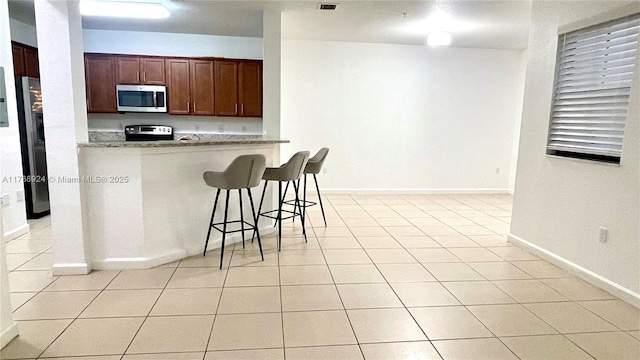 10620 NW 88th St Unit 205, Doral, FL 33178 - kitchen featuring light tile patterned floors, stainless steel appliances, light countertops, a kitchen bar, and baseboards
