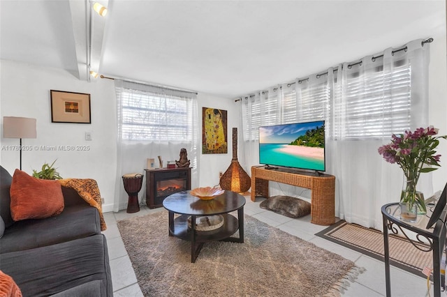 living area featuring a glass covered fireplace and light tile patterned floors