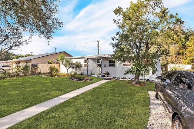 view of front of property featuring fence, a front lawn, and stucco siding