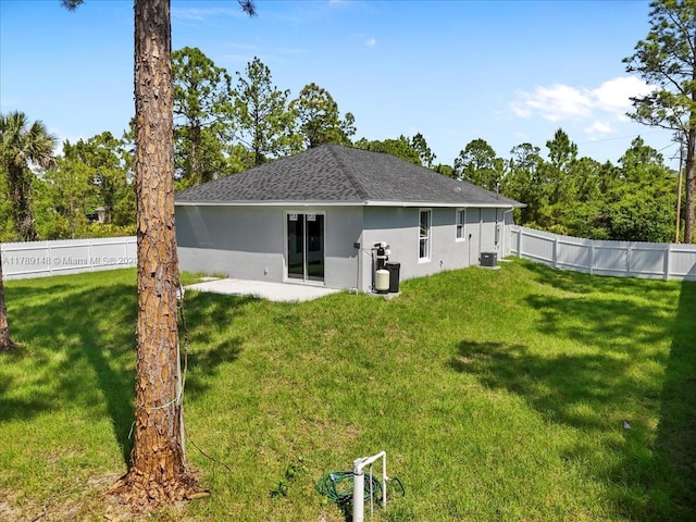 924 Berg St E, Lehigh Acres, FL 33974 - back of house with a fenced backyard, stucco siding, a shingled roof, a patio area, and a lawn